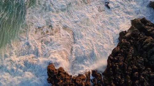 Stormy ocean waves splashing at seashore cliffs volcanic rocks washed by rough swell