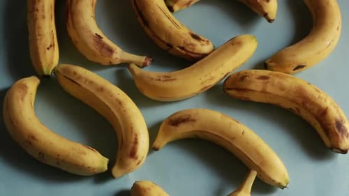 A macro shot of ripe yellow organic bananas rotating against a green background.