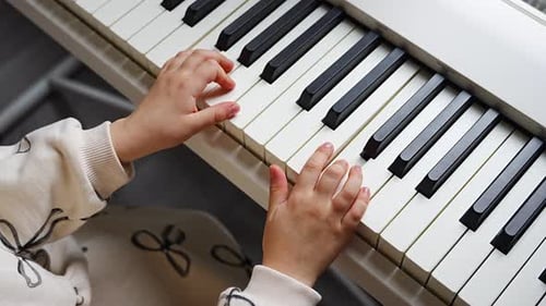 Close Up View of Small Hands of Girl on White Piano Synthesizer Concept of Early Development