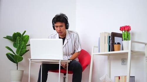 Young Man Video Conferencing at Home on Laptop