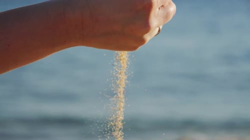 Close Up of Hand Pouring Sand of Beach with Sea Background Sand Spills Out of the Hand Close Up