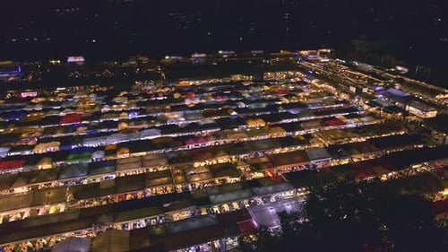 Panning Over Rows of Colorful Market Tents and Food Stalls at Night