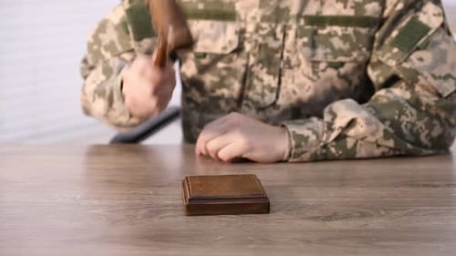 Concepto de ley. Hombre con uniforme militar golpeando un mazo en un escritorio de madera en el interior
, primer plano