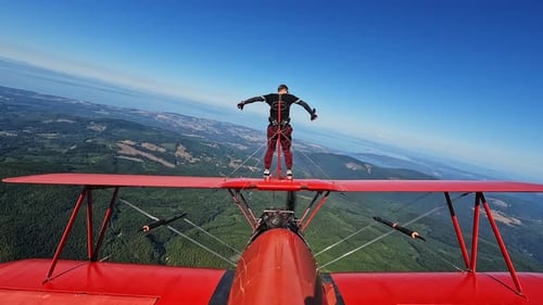 Man Wing Walking on a Red Biplane