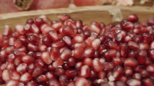 Panning of pomegranate seeds inside wooden plate juicing and using fresh ingredients and fresh whole