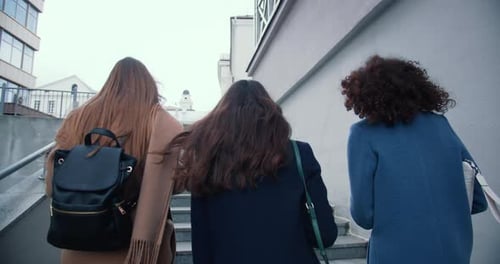 Camera Follows Three Beautiful Happy Business Women Walking Up Stairs in City Downtown Chatting on