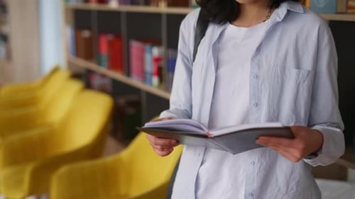 Young female student reading book in a university library