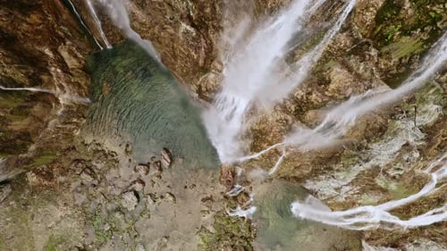 Vista aérea de un Zumbido volador que dispara hermosas cascadas que caen agua de las rocas de las montañas en