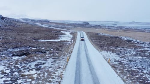 Car Driving Over Snow Covered Road In Landscape