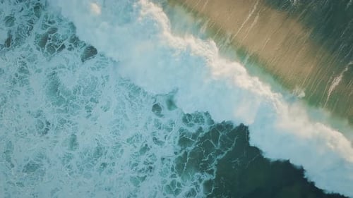 Top down view of big and powerful ocean tide at golden sunset hour. Sea waves creating foam.