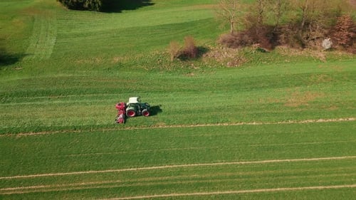 Agriculture farmland. Tractor working on green field