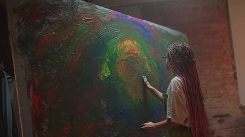 Young Woman with Glasses and Dreadlocks Painting in Studio