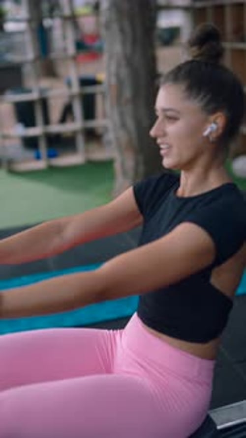 Energetic Woman Exercising on Rowing Machine in Gym