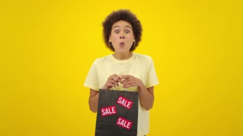Young Woman Looks Into Shopping Bag and Exclaims Admiringly