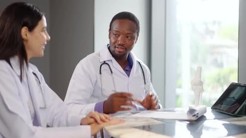 Two doctors engage in an important discussion about patient care at a clinic. They review documents