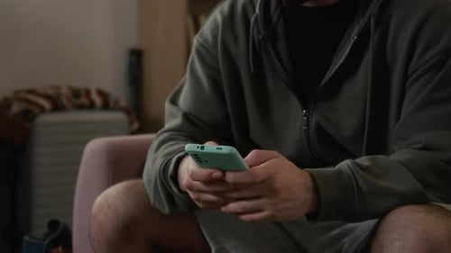 Unrecognizable Young Man Managing Personal Finances on Smartphone at Home
