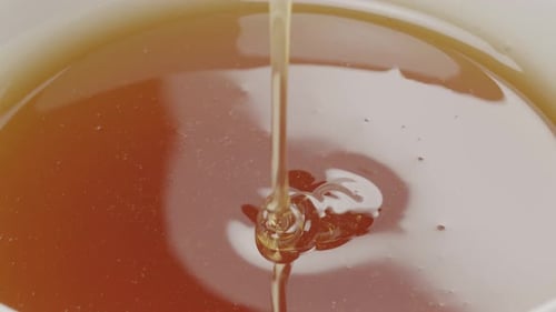 Honey Dipper Stirring Golden Honey in Bowl