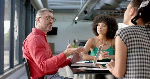 Team of diverse colleagues discussing while sitting together at office