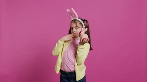 Jolly Schoolgirl Holding a Cute Rabbit Toy and Blowing Kisses in Studio