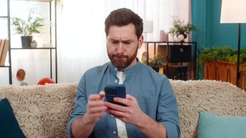 Man Sitting on Couch Using Smartphone Thinking