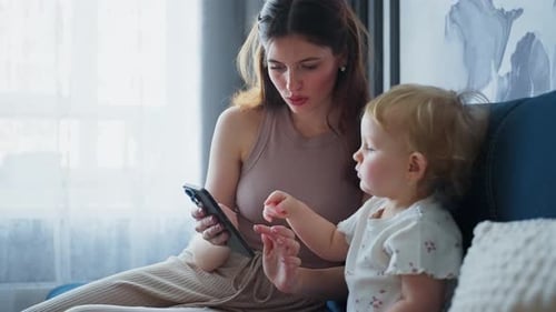 Woman and Child Looking at Smartphone Indoors