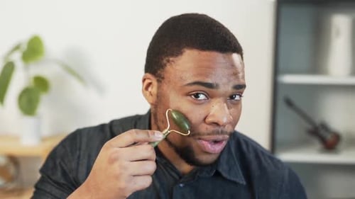 Young Adult Using Jade Roller on Face