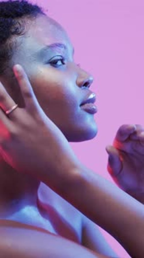 Vertical video of african american woman with dark hair in blue and pink light, slow motion
