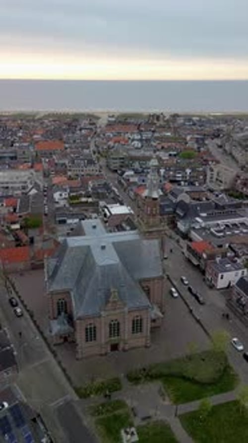 Aerial view coastal town historic church with clock tower rises among red roofs and modern blocks