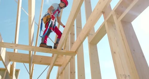 Construction Worker Building Wooden Framework at a Construction Site on a Sunny Day