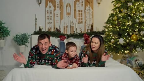 Festive Family Waving on Bed near Christmas Tree