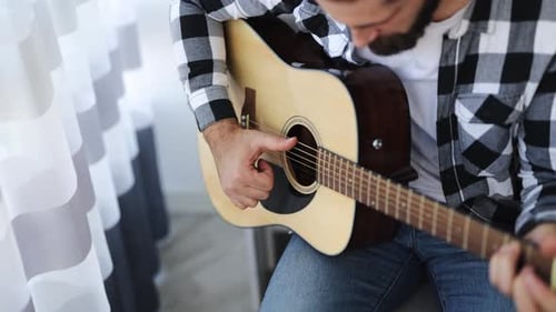Man Plays Acoustic Guitar Indoors During Daytime