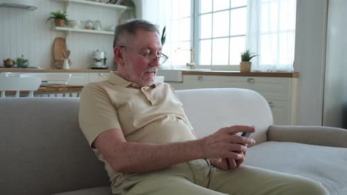 Man Using Smartphone on Couch in Bright Home
