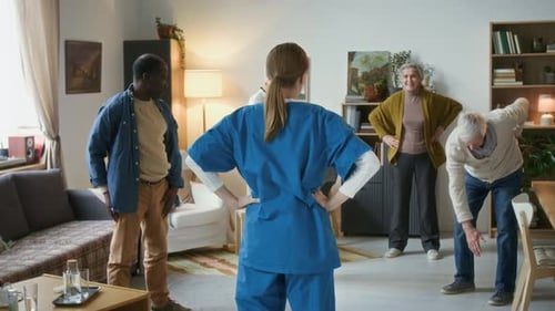 Caregiver Leading Group of Seniors Doing Stretching Exercise in Nursing Home