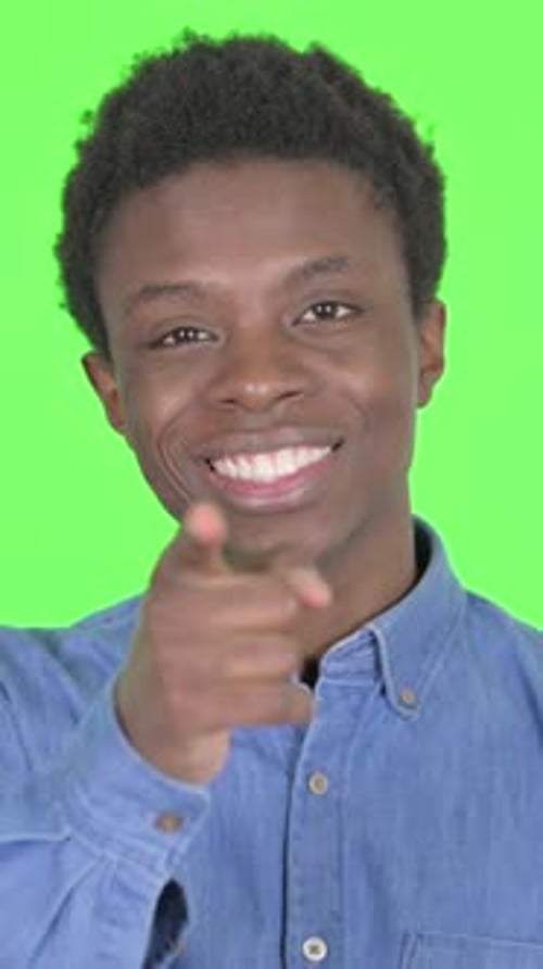 Young African Man Pointing at the Camera on Green Background, Vertical Video