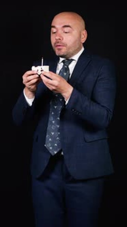Man in Suit Holds Small Cake With Candle