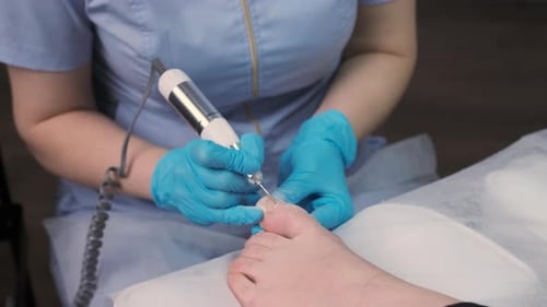 Podologist Doing Professional Medical Pedicure to Young Woman in the Clinic
