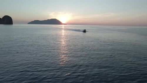 Aerial video of a boat sailing in the sea at sunset