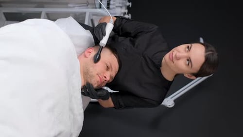 Woman Providing Facial Treatment to Man in Clinic