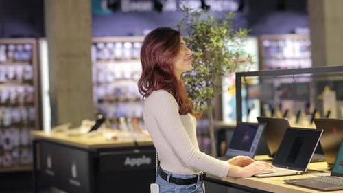 Female Customer Choosing Laptop in the Computer Shop Difficult Decision