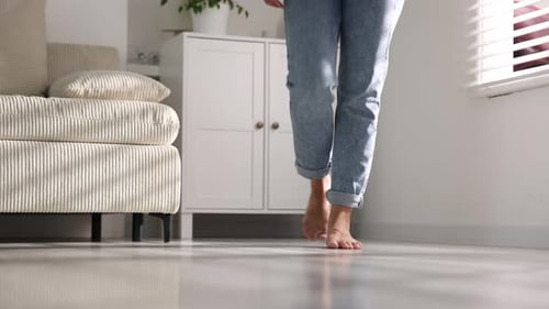 Woman walking barefoot on warm floor at home, closeup. Heating system