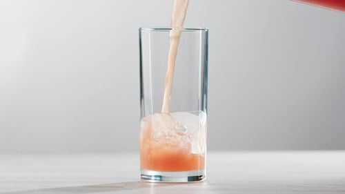 Orange Drink Being Poured into Glass