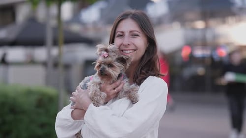 Woman Smiling and Holding Her Dog Outdoors