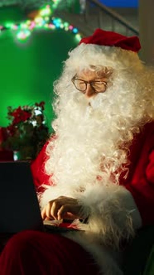 Vertical Video Man Portraying Christmas Character Amused By Children Wish Lists on Laptop