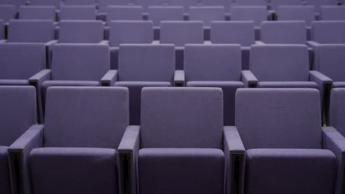 Tilt up on modern empty theatre or auditorium with purple seats
