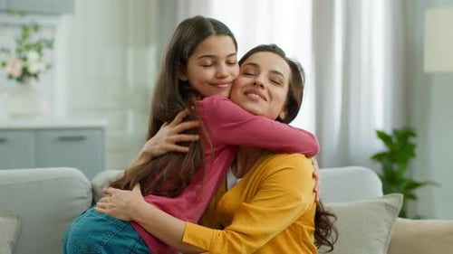 Loving Daughter Embracing Mother on Sofa at Home