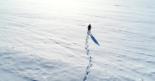 Aerial slow motion view of person walking on a snow