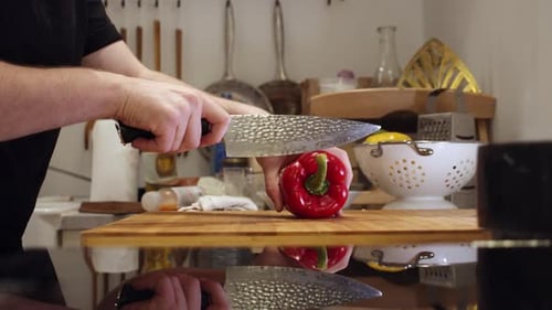 Person Cuts Red Bell Pepper in Home Kitchen