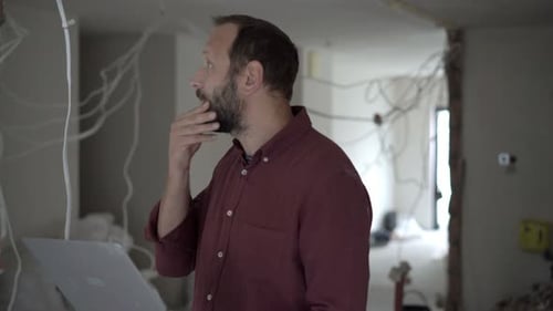 Man Using Laptop in Home Under Construction