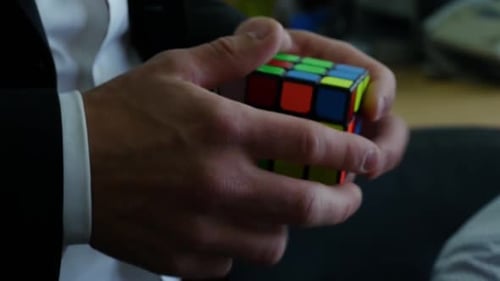 A Person Successfully Manipulating a Rubiks Cube During a Professional Business Environment