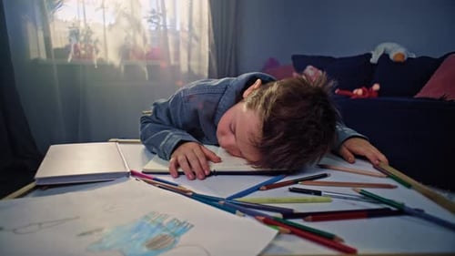 Tired Boy Sleeping on Table with Art Supplies